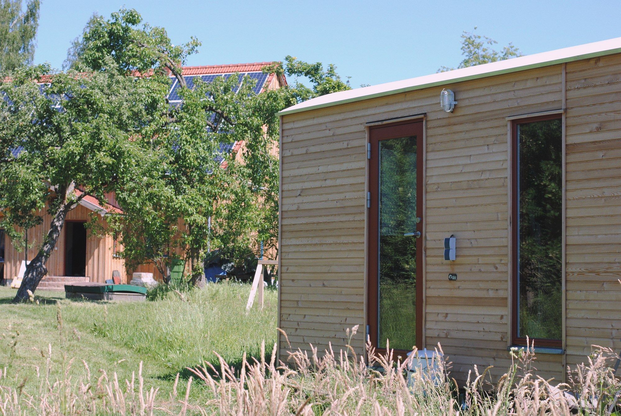 LandAnker Büro im Garten, dahinter Bäume und ein Wohnhaus