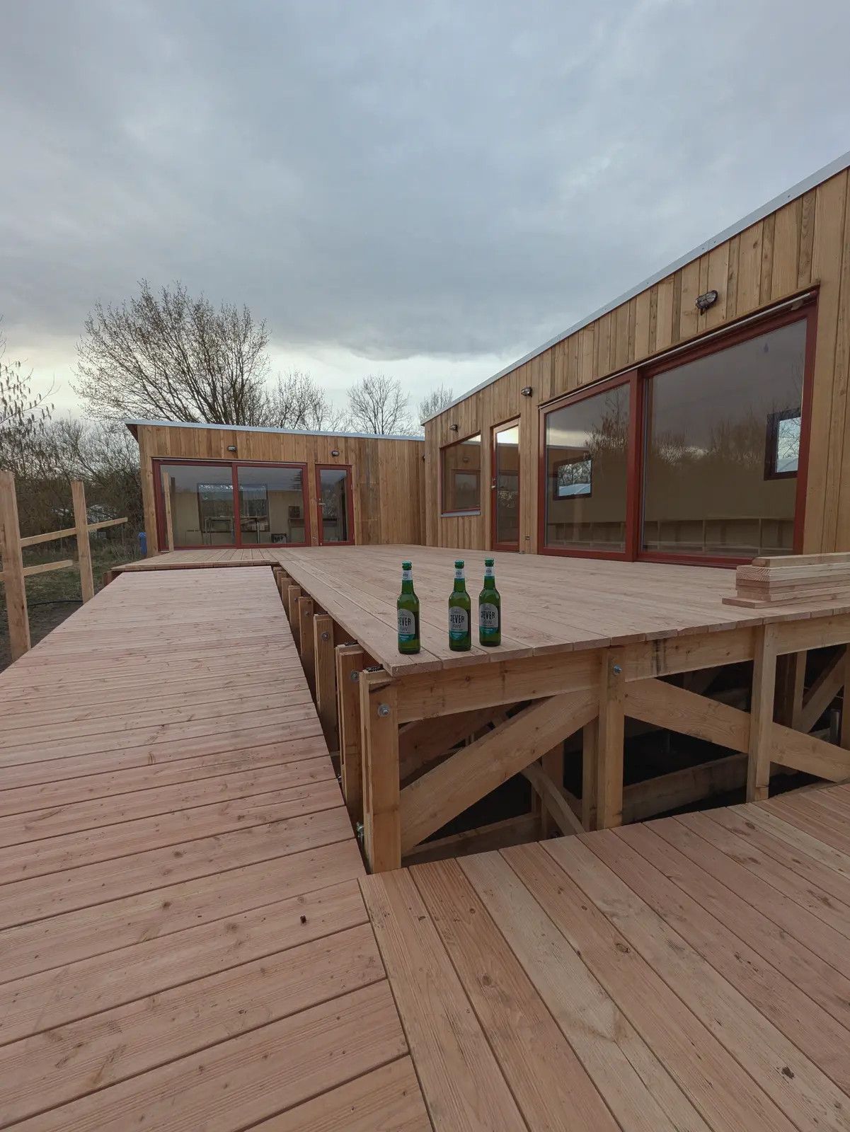 Große Holzterrasse mit Geländer vor zwei über Eck gestellten LandAnkern