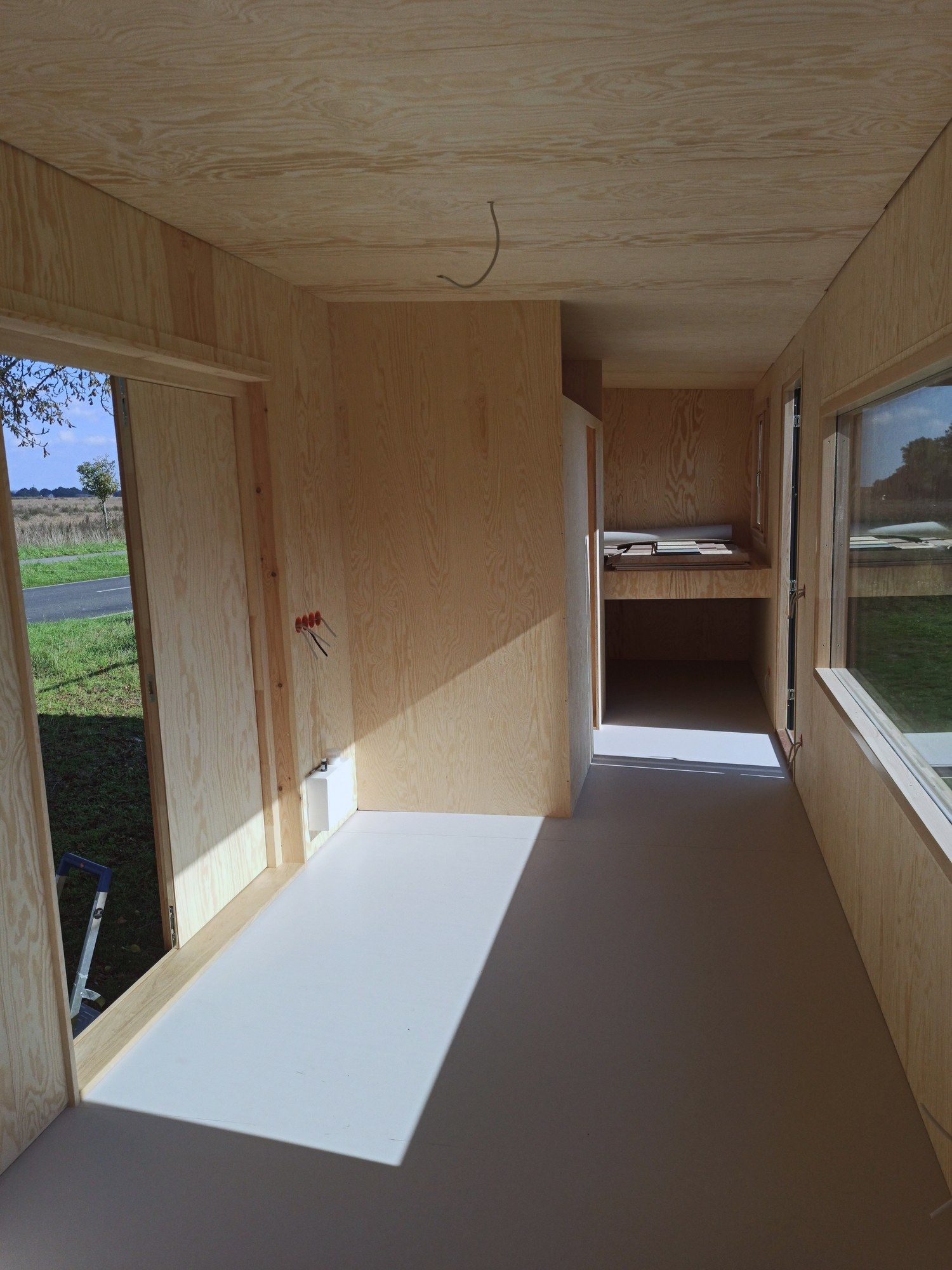 Innenraum aus Birkensperrholz mit einer Bettnische unter dem Fenster